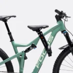 green full suspension bike close-up with a small kids seat attachment on the top tube